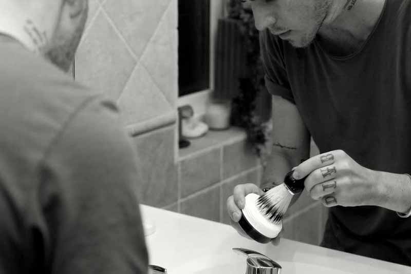 man preparing shaving lather with shaving brush