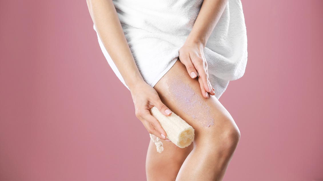female cleaning legs with loofa sponge